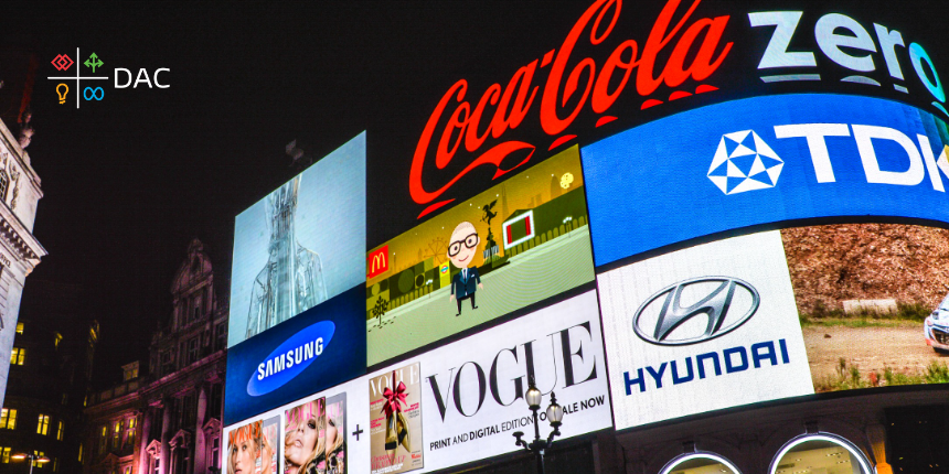 Large digital billboard displays in a cityscape at night, featuring advertisements for brands like Coca-Cola, Samsung, Vogue, Hyundai, and TDK, with DAC logo and icons visible in the top left corner.