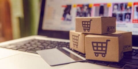 Miniature shopping boxes and a credit card on a laptop keyboard.