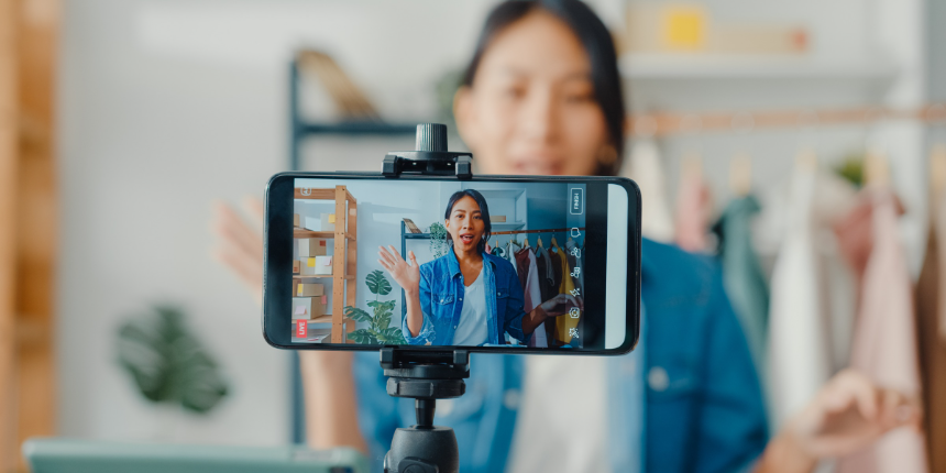 Person recording a vlog with a smartphone on a tripod in front of them.