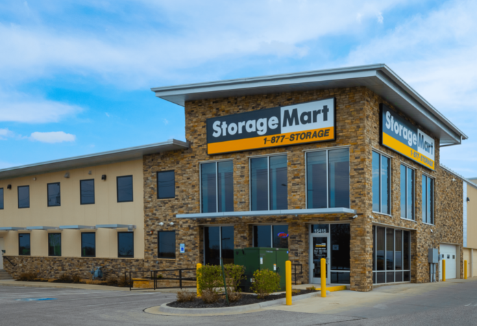 Two-story StorageMart building with stone facade and large glass windows, featuring prominent signage and an accessible entrance.