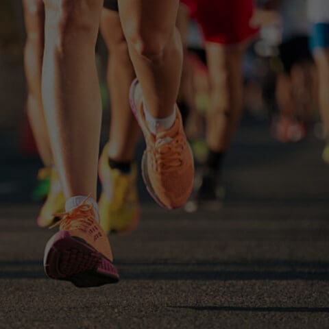 Runners' legs and feet in motion on a roadway during a race.