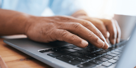 Hands typing on a laptop keyboard.