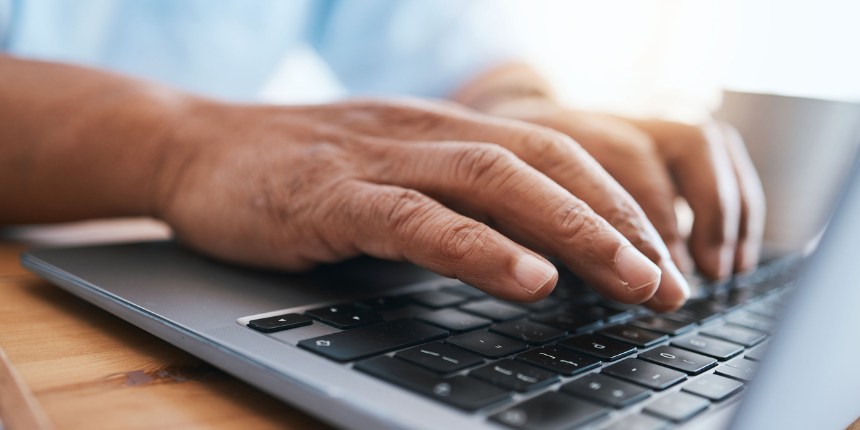 Close-up of hands typing on a laptop keyboard.