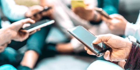 Close-up of multiple hands holding smartphones.