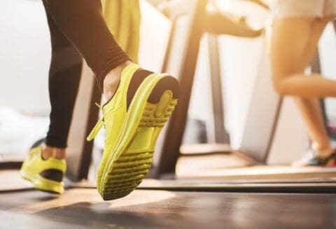 Close-up of a person wearing yellow running shoes on a treadmill.