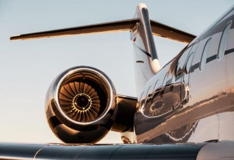 Close-up of a jet engine on a corporate aircraft with a focus on the turbine and tail section against a clear sky.