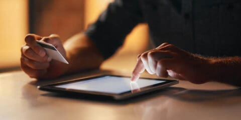 Person using a tablet and holding a credit card.