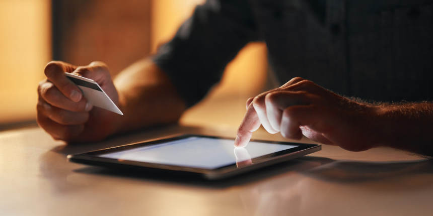 Closeup of hands using a tablet and holding a credit card.