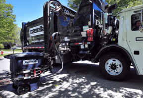 Garbage truck collecting a trash bin on a residential street.