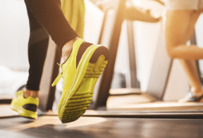 Close-up of people running on treadmills, focusing on bright yellow sneakers.