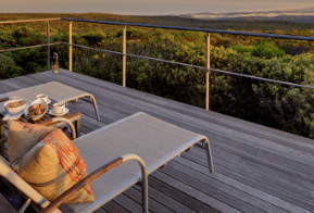 Deck with lounge chairs and breakfast tray overlooking a lush landscape.