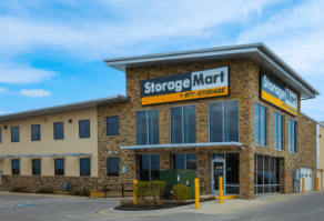 A stone-faced StorageMart building with large windows under a blue sky.