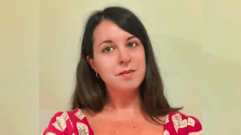 A woman with long dark hair wearing a red and white patterned top.