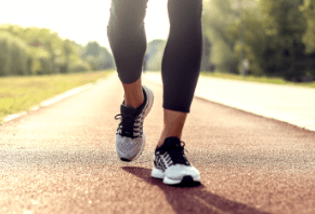 Person walking on a track wearing black leggings and running shoes.