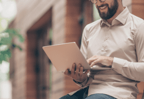 A person sitting outdoors using a tablet.