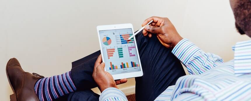 A person holding a tablet displaying various colorful charts and graphs.