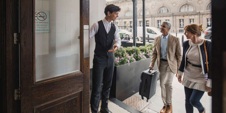 Hotel doorman is welcoming in a mature couple for a weekend break.