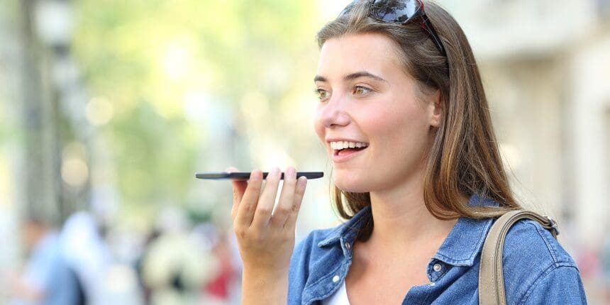 Woman speaking into a smartphone outdoors.