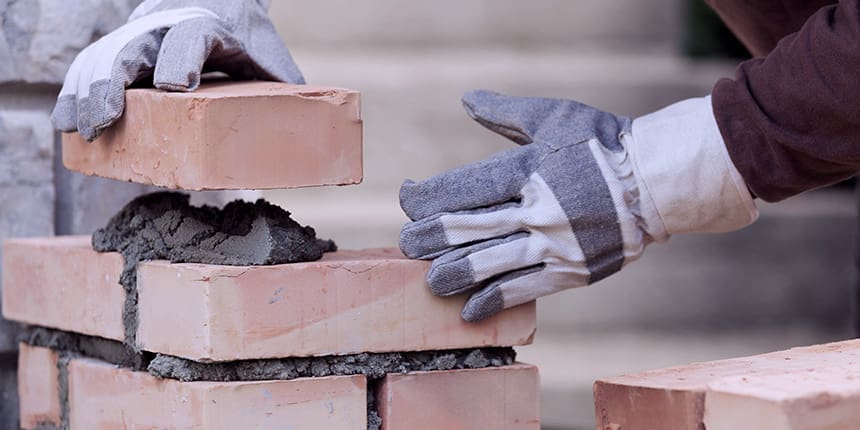 Gloved hands laying bricks