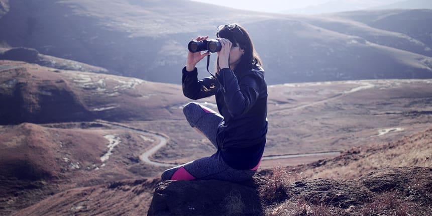 Woman on mountaintop looking through binoculars