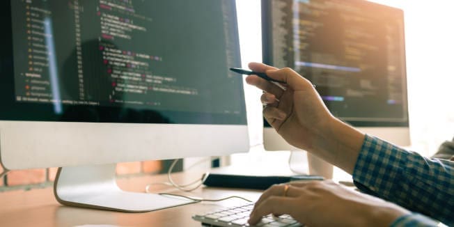 Developing programming working in a software engineers code tech applications on desk in office room.