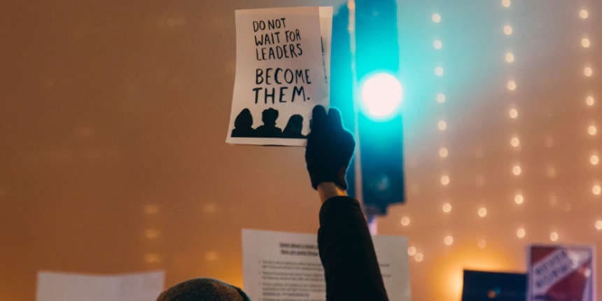 Protester holding sign saying "Do not wait for leaders. Become them."