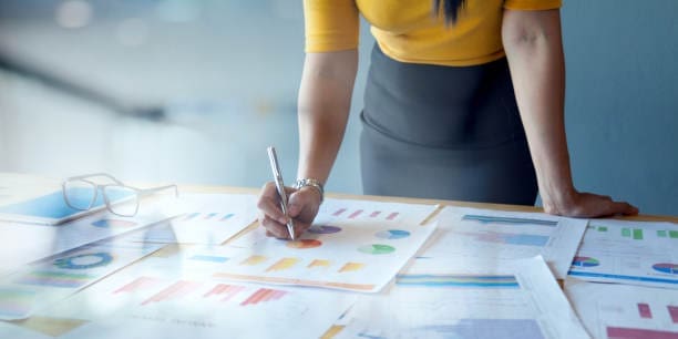 Businesswoman reviewing charts and graphs laid out across her desk