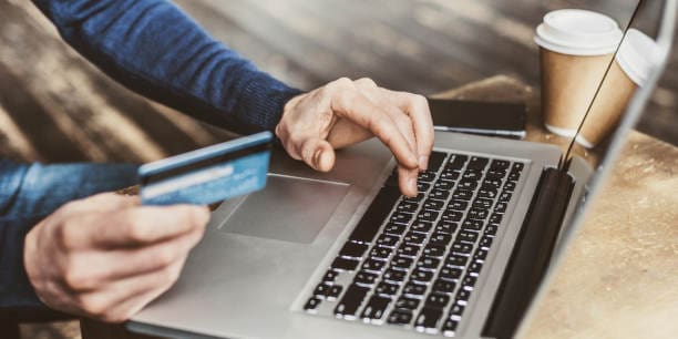 Internet shopper entering credit card information using Mac computer keyboard for online shopping