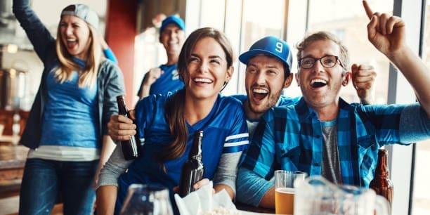 A group of friends cheering while watching a sports game at a bar