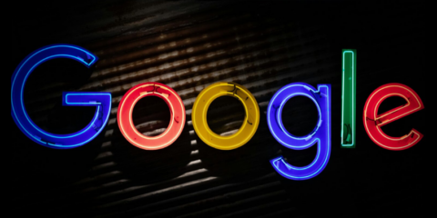 Illuminated Google logo in multi-colored neon lights on a dark background.