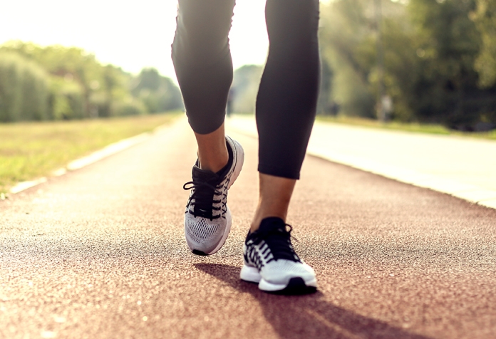 Fotografía de la parte inferior de las piernas trotando a lo largo de una pista de atletismo al aire libre