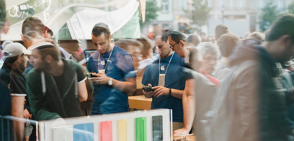 Deux employés d'Apple vus à travers le reflet d'une fênetre sur une rue bondée