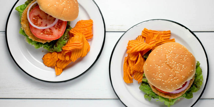 Overhead view of two chicken burger meals on white plates