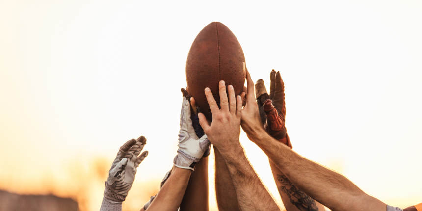 NFL team holding the ball all together