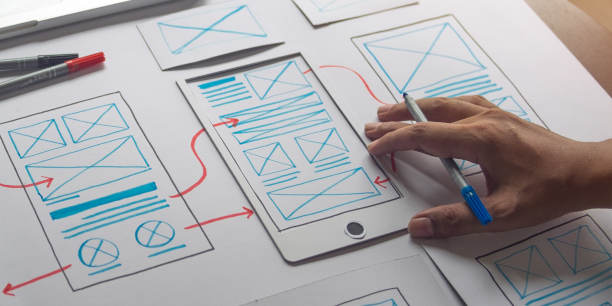 un diseñador de UX dibujando en papel un boceto de una experiencia móvil