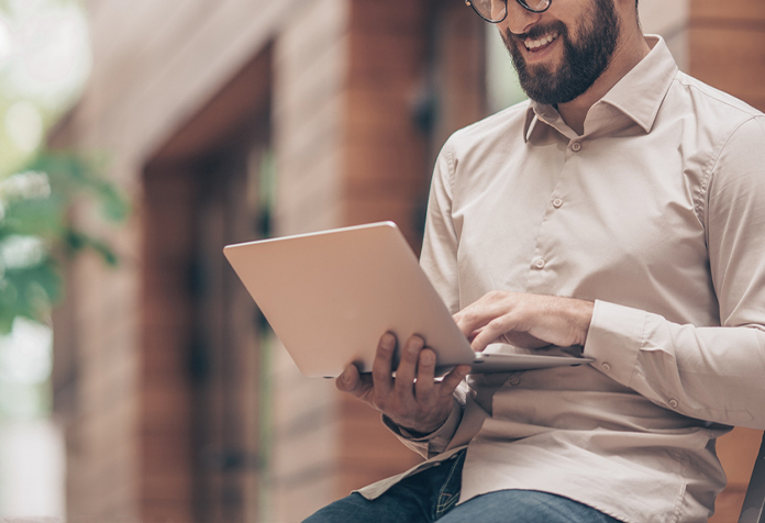 Man with glasses looking at his computer and smiling