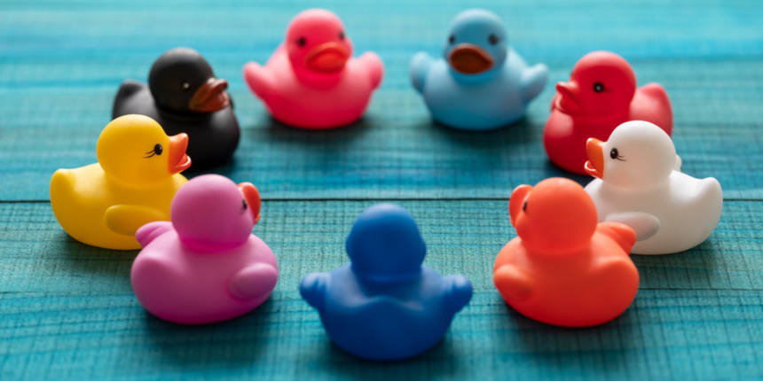 Nine different colored rubber ducks sitting in a circle, as if in a meeting, looking at each other, set on a turquoise colored wood background. Concept image relating to discussing world problems, countries joining together to solve problems, togetherness, harmony, helping, solving problems, uniting, united, global solutions etc.