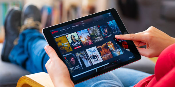 Eine Frau, die einen Tablet-Computer benutzt und eine online Streaming-Plattform sucht.